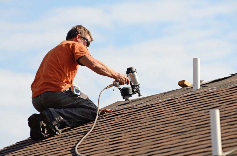 A homeowner using binoculars to inspect a shingled roof with dark streaks and green patches.