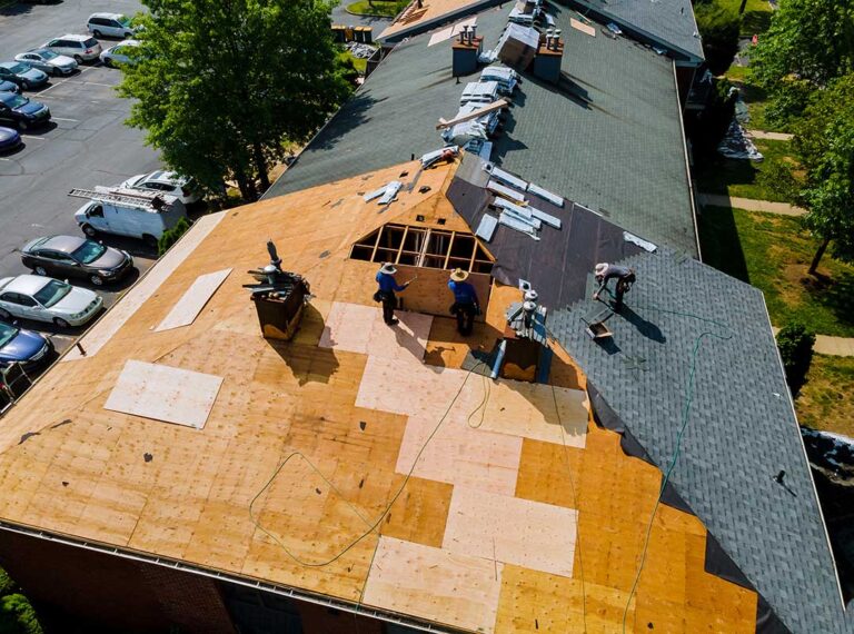 A worker inspecting roof vents and attic insulation on a residential house during early spring.